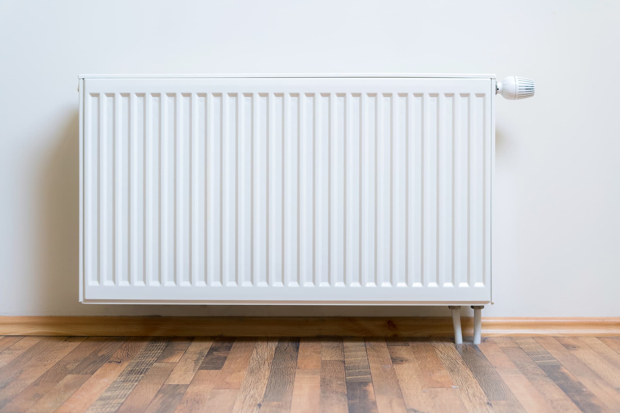 White panel radiator with thermostatic valve on a wall