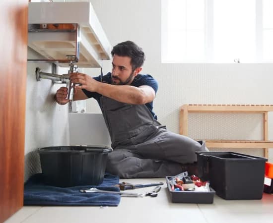 male-plumber-working-to-fix-leaking-sink-in-home-bathroom